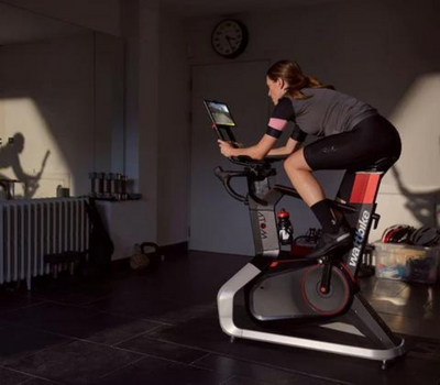 an indoor cyclist in grey clothing workouts on a wattbike indoor bike